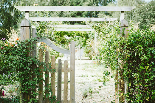 Pforte in einen grünen Garten mit Weg und Pergola